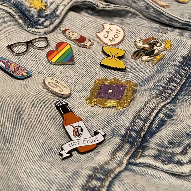 Hot Stuff soft enamel pin on a denim jacket, from a pin collector customer. This hot sauce pin is a spicy way to show off your favorite condiment. Available exclusively here at Revved Up!